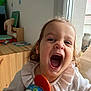 Jade participe au concours pour gagner de l'argent avec cette photo : toddler, child, toy, indoor, window, happy, smiling, face, person, clothing, curly_hair, wooden_furniture, home, playful, colorful, natural_light, sweater, young_child, joyful, closeup