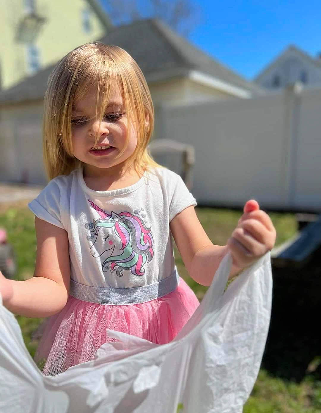 Abby is registered to the contest to win money with this photo: baby_toddler_clothing, blond, child, event, fun, gesture, grass, happy, leisure, magenta, people_in_nature, person, pink, plant, play, recreation, sitting, sky, t_shirt, toddler