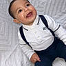 Marwan a rejoint le concours — aidez-le/la à gagner de superbes lots ! baby, child, smiling, white_shirt, suspenders, navy_pants, cute, portrait, happy, indoors, texture, blanket, sitting, face, person, infant, young_child, clothing, joyful, expression