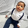 Marwan a rejoint le concours — aidez-le/la à gagner de superbes lots ! toddler, child, baby, sitting, white_polo_shirt, navy_pants, suspenders, couch, cushions, geometric_pattern, indoor, portrait, face, curious_expression, short_hair, clothing, home, soft_lighting, person, young