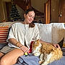 Romy participe au concours pour gagner de l'argent avec cette photo : woman, cat, indoor, sofa, blanket, christmas_tree, stairs, wooden_furniture, smiling, petting, cozy, decor, orange_cat, white_cat, jewelry, casual_clothing, relaxing, home, furniture, holiday