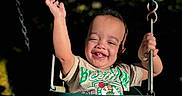 Jayden is registered to the contest to win money with this photo: chains, child, clothing, daylight, fun, happy, joy, nature, outdoor, person, play, playground, portrait, seat, shirt, shorts, smiling, sunlight, swing, toddler