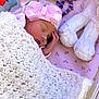newborn, baby, sleeping, blanket, pink_headband, bow, soft_toys, plush, white_blanket, floral_sheet, infant, cute, peaceful, cozy, child, resting, indoors, closeup, adorable, toddler