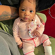 Khazi Khapri is registered to the contest to win money with this photo: baby, infant, child, portrait, sitting, indoors, pink_outfit, bow, pacifier, teether, name_beads, socks, green_seat, car_seat, adult_arm, tattoo, close_up, wide_eyes, serious_expression, cozy