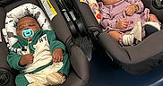 Khazi Khapri is registered to the contest to win money with this photo: babies, infants, sleeping, car_seats, indoors, portrait, pacifier, pink_outfit, green_outfit, floral_padding, blanket, buckled, transportation, nursery, safety_labels, seated, peaceful, siblings, photograph, cute
