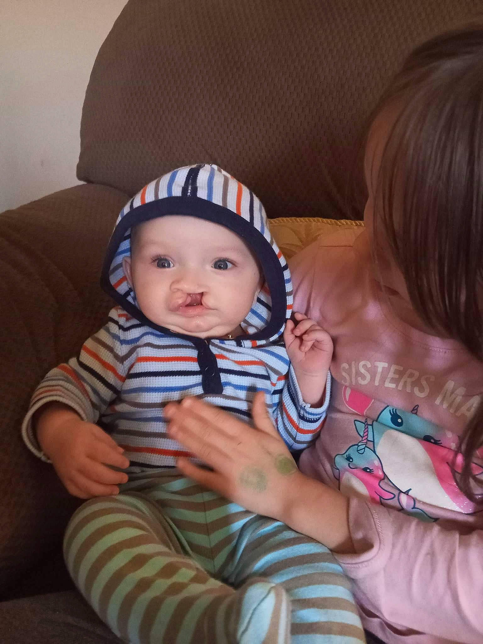 Braxton is registered to the contest to win money with this photo: arm, baby, baby_toddler_clothing, cheek, child, comfort, couch, facial_expression, fun, hand, happy, headwear, iris, lap, nail, nose, person, sitting, skin, smile