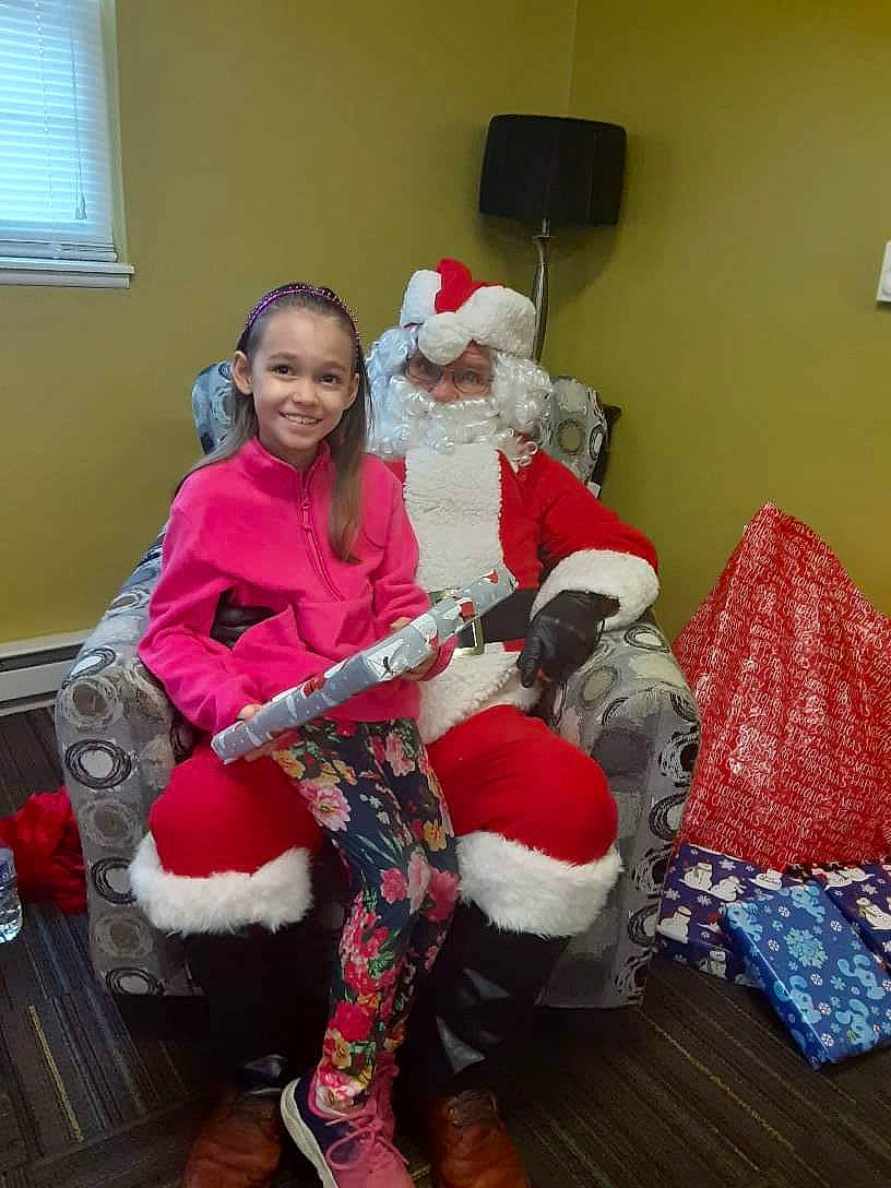 Lexi is registered to the contest to win money with this photo: christmas, christmas_decoration, christmas_eve, christmas_ornament, comfort, event, fictional_character, fur, happy, hat, holiday, joy, lap, person, room, santa_claus, sitting, smile, textile, thigh