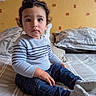 Lorenzo participe au concours pour gagner de l'argent avec cette photo : bed, casual_clothing, child, cozy, curly_hair, cute, home, indoor, jeans, looking_at_camera, pillow, portrait, red_pattern, seated, socks, soft_lighting, striped_sweater, toddler, yellow_wall, young_child