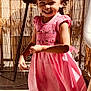 child, girl, pink_dress, smile, curly_hair, outdoor, balcony, sunlight, shadow, happy, socks, concrete_floor, fence, furniture, person, playful, daylight, motion, joy, casual