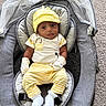 baby, infant, child, yellow_hat, yellow_pants, striped_clothing, white_socks, white_mittens, baby_seat, gray_cushion, carpet, indoor, portrait, cute, smiling, relaxed, comfortable, baby_fashion, newborn, soft_textures