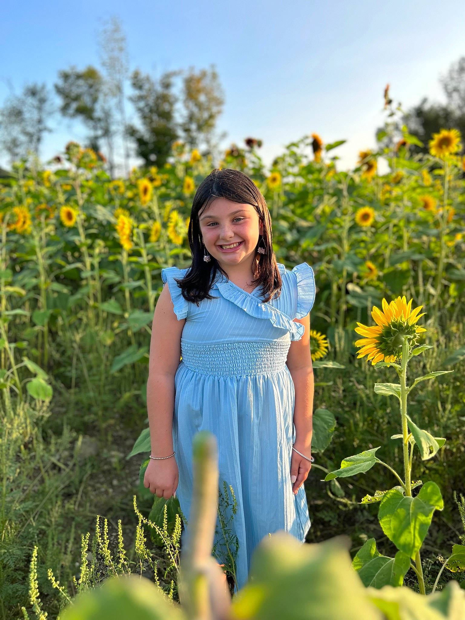 Delilah is registered to the contest to win money with this photo: day_dress, dress, flower, grass, grass_family, grassland, hair, happy, headwear, joy, meadow, morning, natural_environment, one_piece_garment, people_in_nature, person, petal, plant, sky, smile