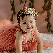 Stella is registered to the contest to win money with this photo: baby, child, dress, flower_crown, headband, smile, cute, portrait, indoor, fluffy_rug, pink, child_crawling, happy, young, person, toddler, skin, hair, face, background