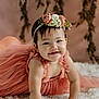 baby, child, dress, flower_crown, headband, smile, cute, portrait, indoor, fluffy_rug, pink, child_crawling, happy, young, person, toddler, skin, hair, face, background