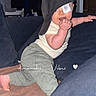 baby, child, cap, crawling, finger_in_mouth, blanket, cushion, clothing, indoors, person, cute, smiling, face, tag, furniture, home, cozy, playful, expression, infant