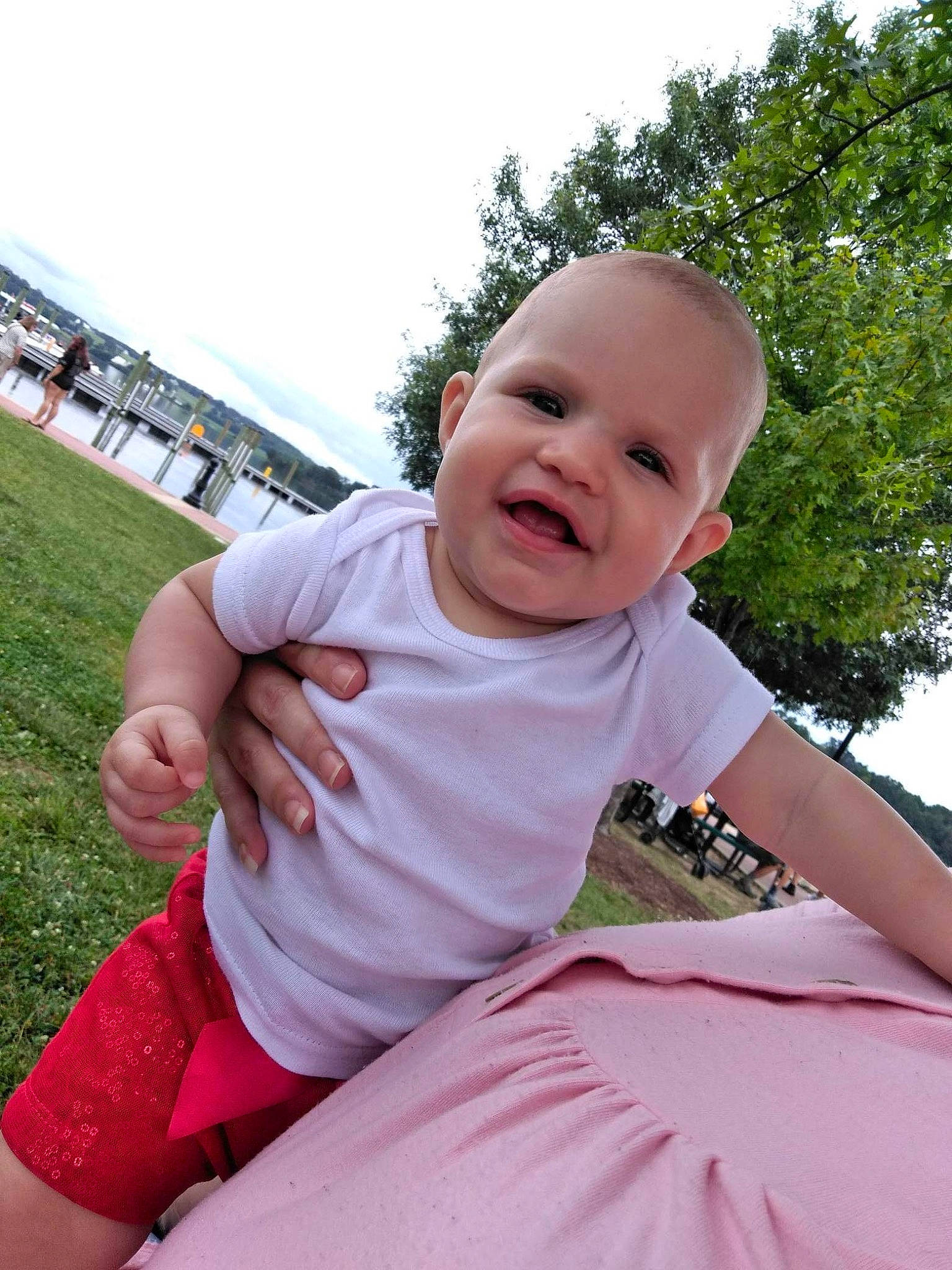 Leilani is registered to the contest to win money with this photo: baby, baby_laughing, baby_toddler_clothing, child, fun, grass, happy, joy, leisure, magenta, person, pink, plant, recreation, shorts, sitting, sky, sleeve, smile, t_shirt