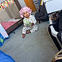 baby, child, indoor, carpet, playpen, car_seat, pajamas, bonnet, snack, floor, door, drawer, furniture, toy, room, person, sitting, holding, cute, infant