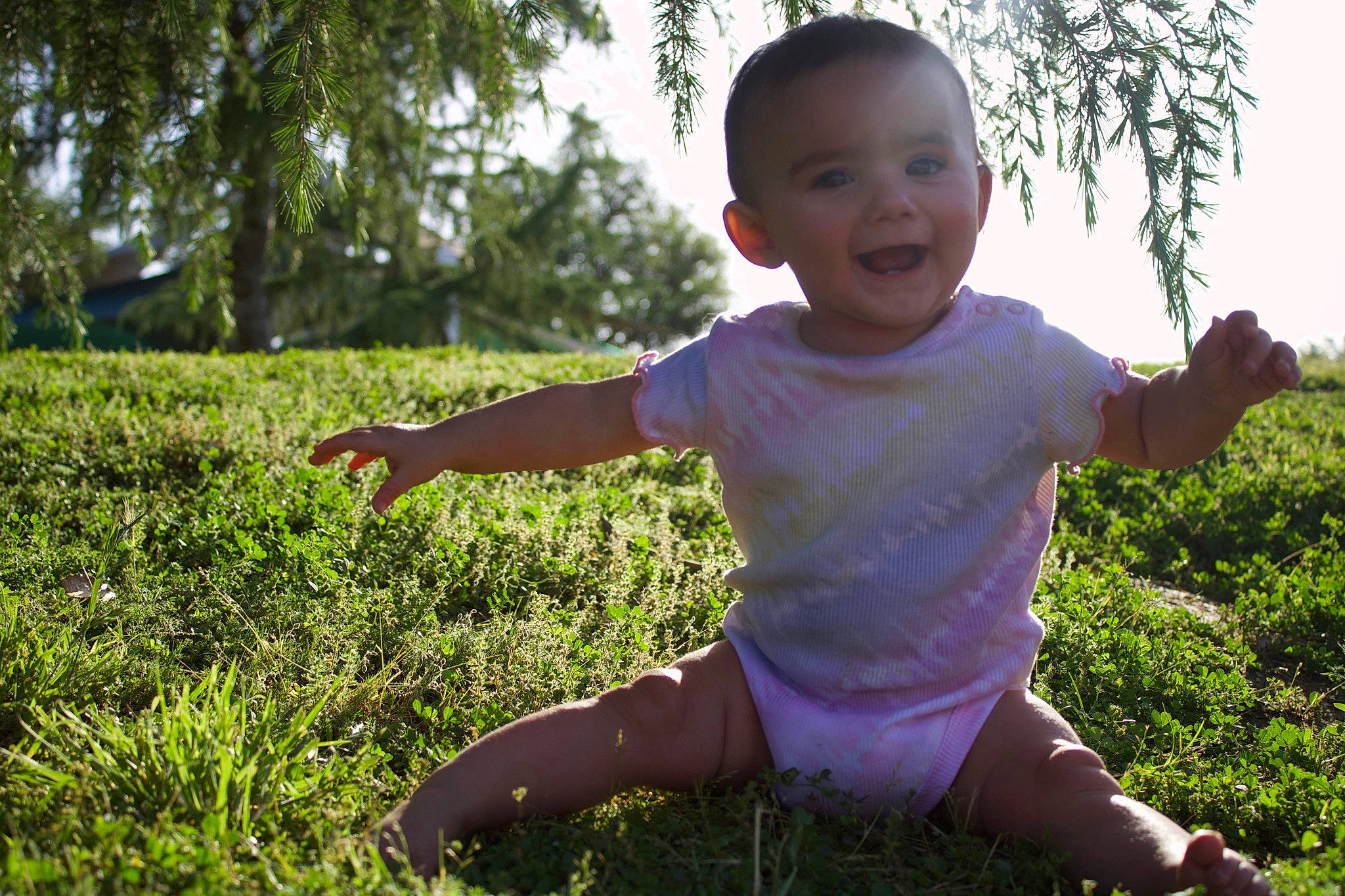 Juliana is registered to the contest to win money with this photo: baby_toddler_clothing, facial_expression, gesture, grass, grass_family, grassland, happy, joy, leaf, leisure, meadow, people_in_nature, person, plant, sky, sleeve, smile, summer, sunlight, t_shirt
