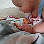 Evalynn joined the competition — help win amazing prizes! baby, blanket, candid, child, closeup, clothing, curious, face, focus, food_bag, hand, indoors, infant, person, resting, side_view, skin, snack, soft_texture, young_child
