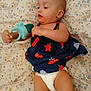 baby, bed, blue, calm, child, curious, diaper, dress, face, floral_bed_sheet, hand, indoor, infant, lying_down, person, red, skin, soft_lighting, stars, toy