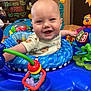 baby, smiling, activity_center, toy, colorful, indoor, child, infant, happy, play, seat, face, clothing, furniture, background, decor, person, cute, expression, room