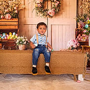 Jonathan is registered to the contest to win money with this photo: toddler, child, boy, sitting, blue_shirt, suspenders, jeans, black_shoes, easter_eggs, flower_wreath, wooden_crates, flowers, pastel_colors, rustic, bench, indoor, decor, spring, cute, portrait