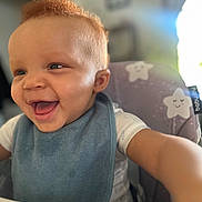 Naveen joined the competition — help win amazing prizes! baby, smiling, high_chair, bib, red_hair, happy, child, indoor, portrait, cute, face, expression, toddler, clothing, person, seat, fun, joy, infant, reaching