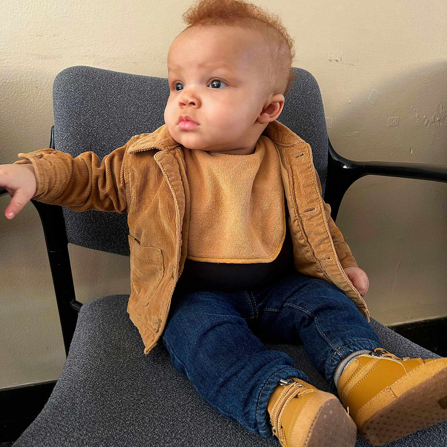 Naveen is registered to the contest to win money with this photo: baby, child, chair, jacket, denim, boots, footwear, clothing, seated, indoor, curly_hair, fashion, portrait, cute, infant, looking_away, expression, toddler, furniture, casual