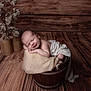 Arthur a rejoint le concours — aidez-le/la à gagner de superbes lots ! newborn, baby, sleeping, wooden_bucket, fabric, blanket, rustic, wooden_floor, wooden_wall, dried_flowers, vase, peaceful, portrait, infant, soft_lighting, cozy, wrapped, cute, indoors, resting