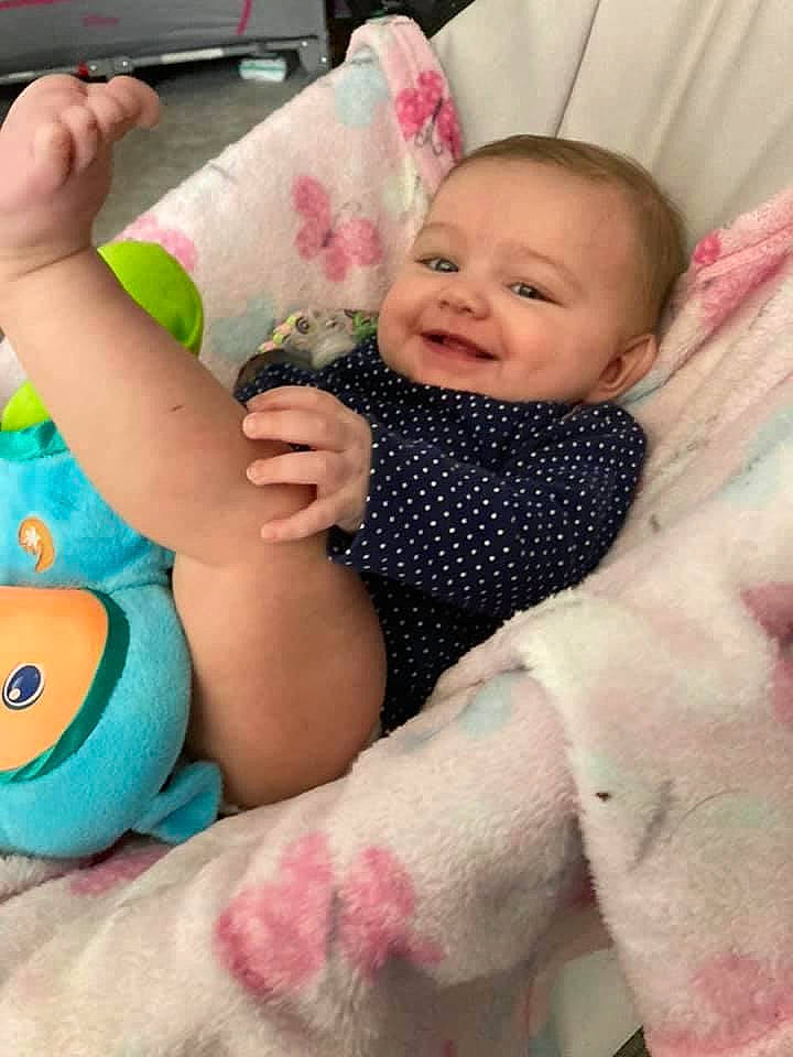 Ava is registered to the contest to win money with this photo: baby, baby_toddler_clothing, cheek, child, comfort, eye, face, finger, green, happy, head, human_body, joy, person, photograph, pink, skin, smile, sock, textile