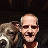 Virgel is registered to the contest to win money with this photo: man, dog, pet, portrait, closeup, smile, face, canine, indoor, light, shadow, adult, animal, friendship, head, skin, fur, collar, nose, expression