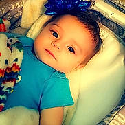 Amia is registered to the contest to win money with this photo: baby, infant, blue_bow, blanket, basket, cushion, face, head, eyes, clothing, indoor, table, chair, wood, portrait, cute, child, laying, comfort, cozy