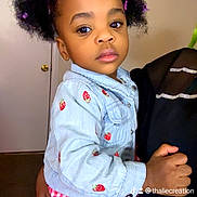Khloe is registered to the contest to win money with this photo: child, toddler, person, denim_jacket, strawberry_embroidery, red_checkered_skirt, hair_clips, curly_hair, indoor, door, adult_hand, holding, portrait, face, expression, clothing, cute, young_child, fashion, standing
