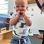 Hendrix is registered to the contest to win money with this photo: toddler, child, smiling, happy, indoor, clothing, dinosaur_print, shirt, denim_pants, standing, blue_eyes, blond_hair, playroom, carpet, toy, furniture, person, portrait, cute, young_child