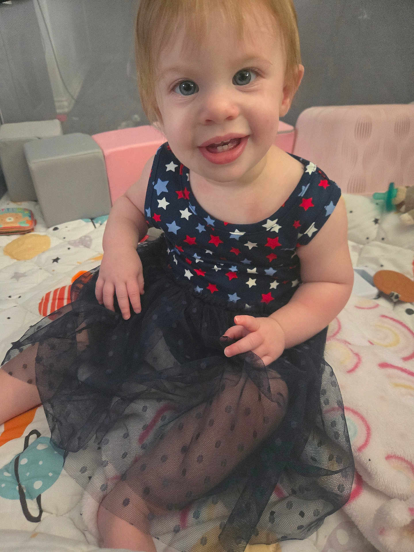 Elena joined the competition — help win amazing prizes! toddler, child, smiling, dress, stars, polka_dot, sitting, quilt, indoor, happy, face, hand, blue_eyes, short_hair, colorful, toy, blanket, play_area, cute, portrait