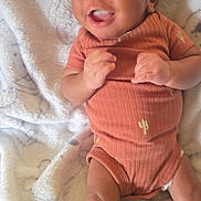 Jimmy joined the competition — help win amazing prizes! baby, infant, onesie, orange_clothing, cactus_print, blanket, soft_texture, lying_down, smiling, cute, small_hands, legs, socks, indoors, portrait, child, happy, face, skin, newborn