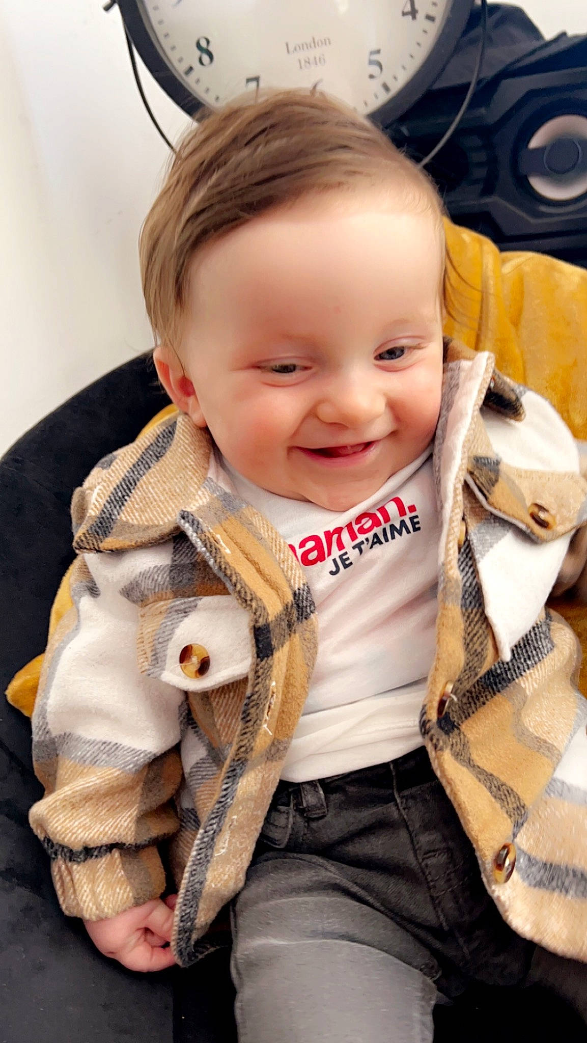 Milo participe au concours pour gagner de l'argent avec cette photo : baby, baby_products, baby_toddler_clothing, cheek, child, eye, face, fashion_accessory, fun, happy, head, iris, joy, person, personal_protective_equipment, plaid, sitting, skin, sleeve, smile