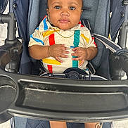 Jhamir is registered to the contest to win money with this photo: baby, child, stroller, colorful_clothing, striped_shirt, shoes, infant, seatbelt, portrait, cute, indoor, person, hands, face, eyes, expression, casual, young_child, seat, footwear