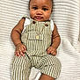 Jhamir joined the competition — help win amazing prizes! baby, infant, child, overalls, striped_clothing, necklace, gold_chain, sitting, blanket, soft_texture, cute, portrait, smiling, happy, chubby_cheeks, indoors, comfort, skin, hand, foot