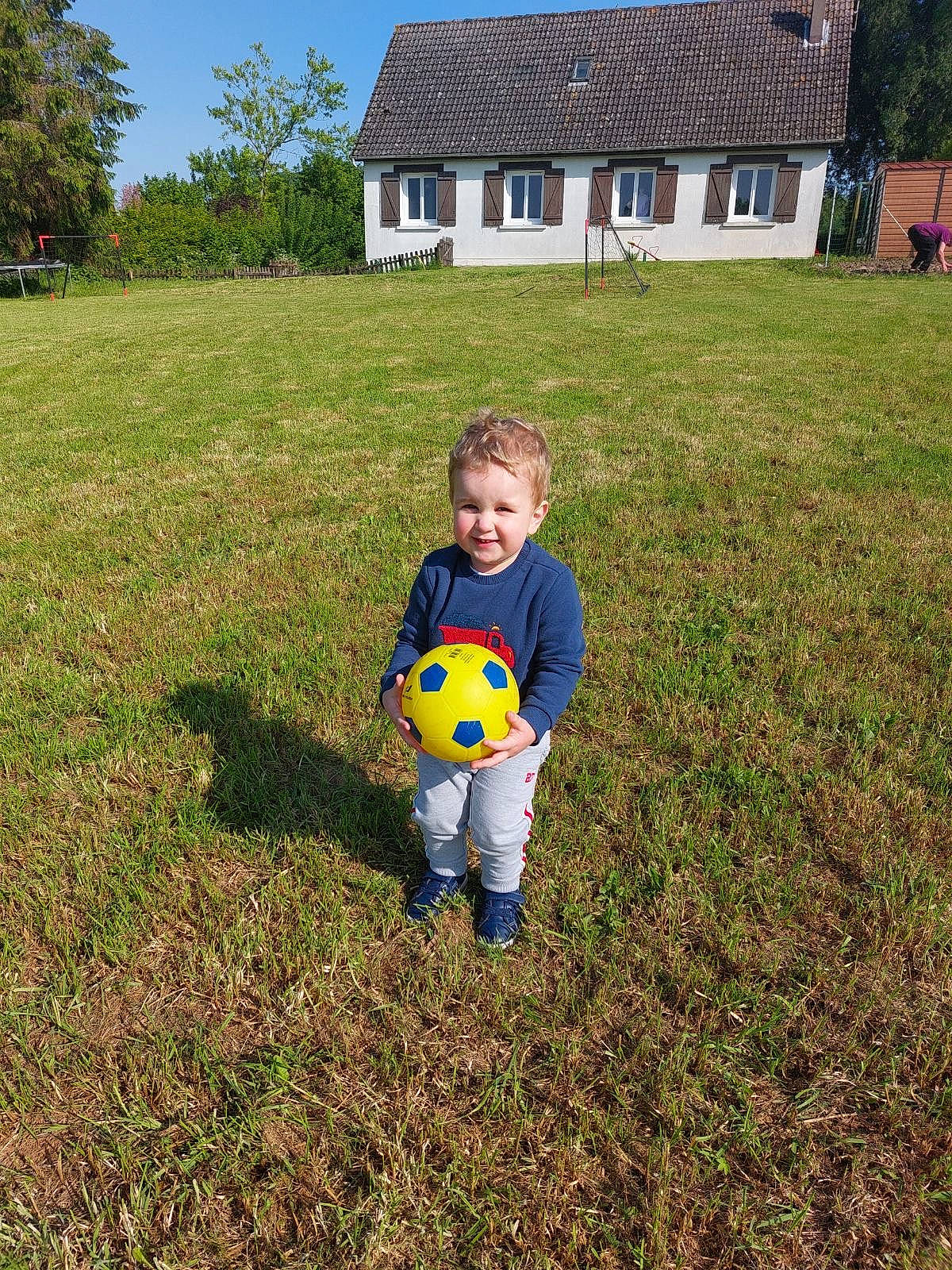 Lorenzo a rejoint le concours — aidez-le/la à gagner de superbes lots ! ball, football, grass, grassland, happy, house, joy, meadow, natural_environment, people_in_nature, person, plant, player, sky, smile, soccer, soccer_ball, sports_equipment, t_shirt, toddler