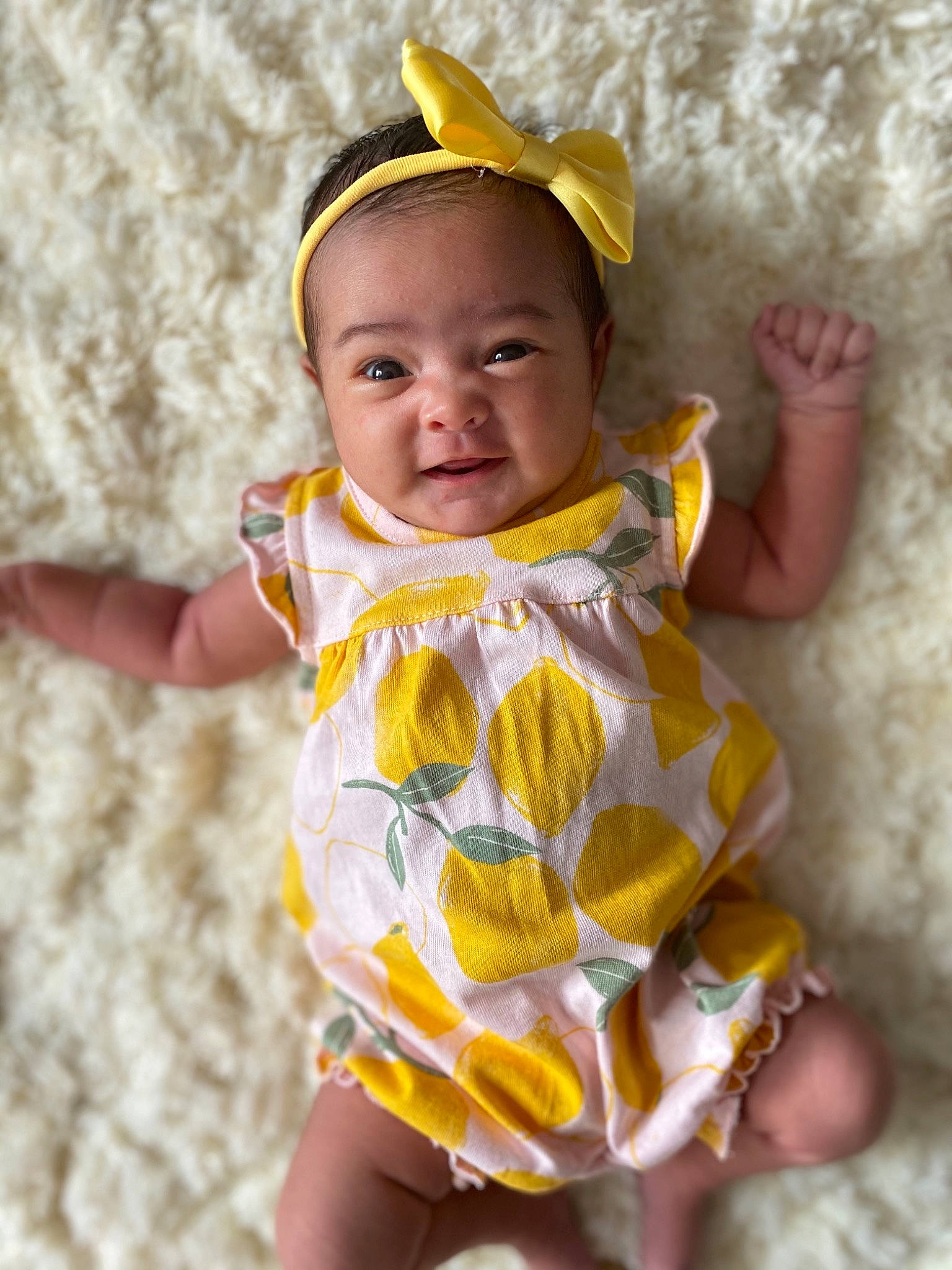 Lilyana is registered to the contest to win money with this photo: baby, baby_toddler_clothing, cheek, child, eyelash, fashion_accessory, grass, happy, human_body, lip, pattern, person, pink, sitting, skin, sleeve, smile, t_shirt, thumb, toddler