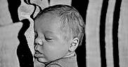 Rodrick is registered to the contest to win money with this photo: baby, black_and_white, blanket, close_up, clothing, cozy, crib, eyes_closed, face, indoors, infant, newborn, peaceful, photography, portrait, resting, side_profile, sleeping, soft_lighting, toddler