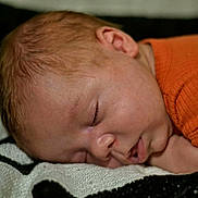 Rodrick is registered to the contest to win money with this photo: baby, blanket, close_up, closed_eyes, cozy, curled_up, ear, face, head, indoors, infant, newborn, nose, orange_clothing, peaceful, photography, portrait, resting, sleeping, soft_blanket