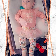 Khaleesi is registered to the contest to win money with this photo: baby, blanket, child, cushion, cute, floral_leggings, frame, girl, indoor, infant, lying_down, marble_background, mittens, pacifier, pink_clothing, portrait, smiling, soft_lighting, toy, tutu