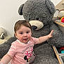 carpet, casual_clothing, child, cute, floor, gray, happy, indoor, minnie_mouse, pink_shirt, playroom, plush_toy, reaching, sitting, soft, stuffed_animal, teddy_bear, toddler, toy_storage, young_child