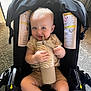 Braxton is registered to the contest to win money with this photo: baby, child, car_seat, sippy_cup, infant, cute, indoor, carrying, holding, seated, carpet, sunlight, curtain, shorts, tshirt, smiling, face, hands, foot, comfort