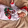 baby, christmas, holiday_clothing, santa_hat, reindeer_slippers, blanket, infant, cute, festive, warm, sleepwear, soft, portrait, lying_down, holiday, child, smiling, indoors, happy, cozy