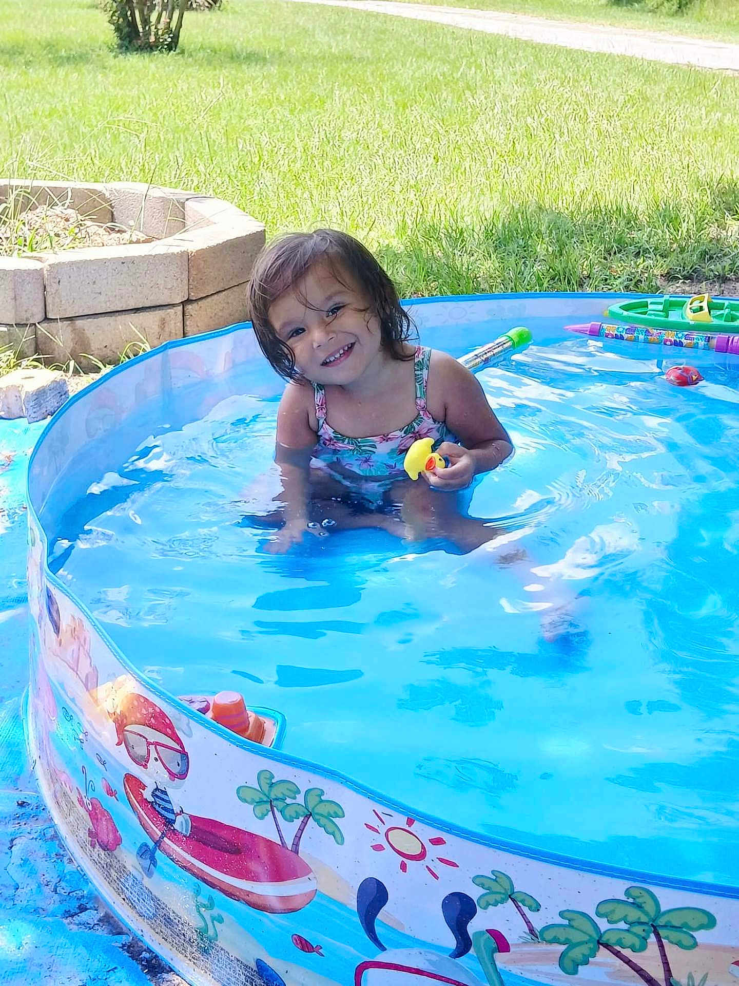 Kellcey joined the competition — help win amazing prizes! child, toddler, pool, water, toy, rubber_duck, smile, outdoor, grass, splash, summer, swimsuit, inflatable_pool, play, happy, sunlight, face, person, greenery, plastic