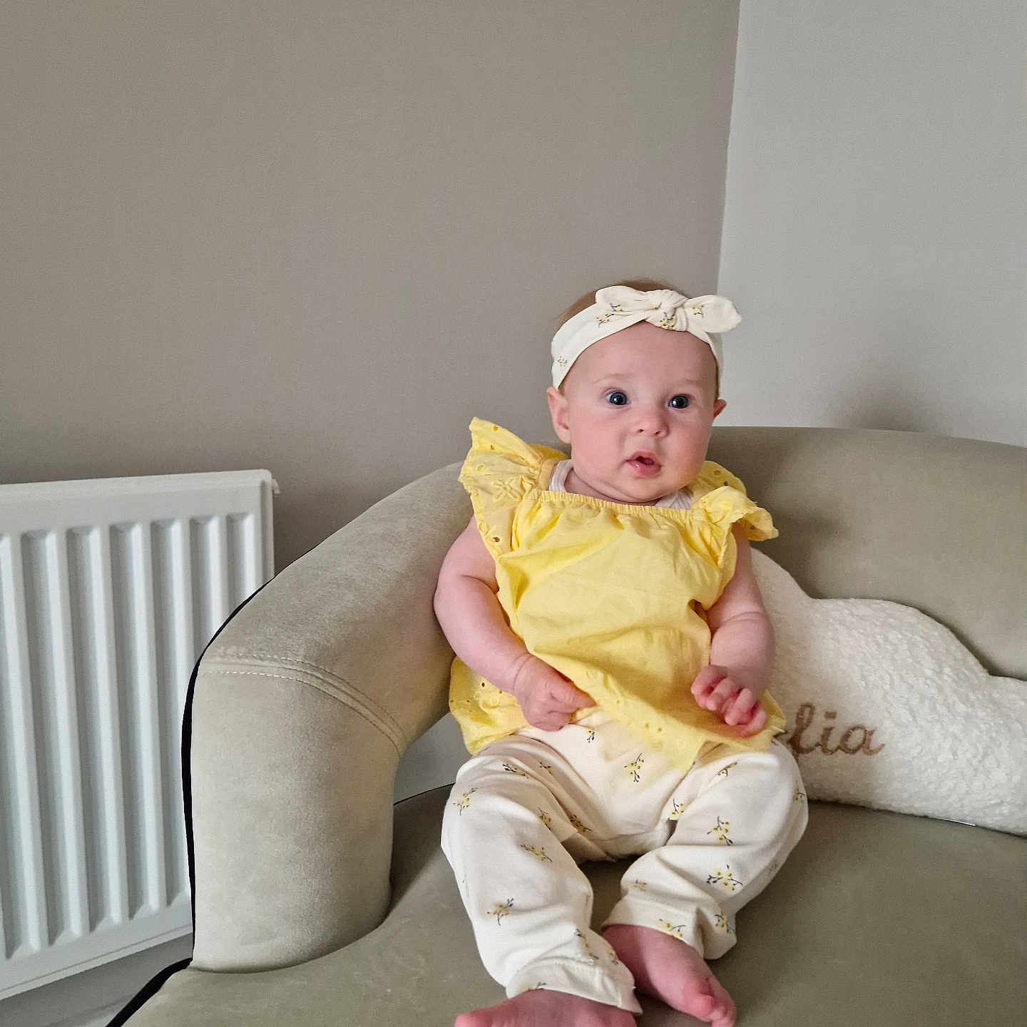 Sofia joined the competition — help win amazing prizes! baby, barefoot, casual_clothing, child, comfort, couch, curious_expression, cushion, headband, home_interior, indoor, infant, pants, person, portrait, radiator, seated, soft_lighting, yellow_clothing, young_child
