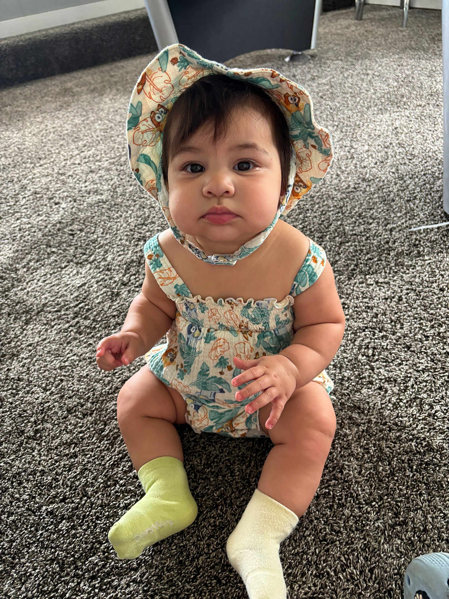Lyla joined the competition — help win amazing prizes! baby, child, sitting, hat, romper, carpet, indoor, cute, sock, mismatched_socks, curious, portrait, infant, chubby_cheeks, person, clothing, floor, closeup, young_child, headwear