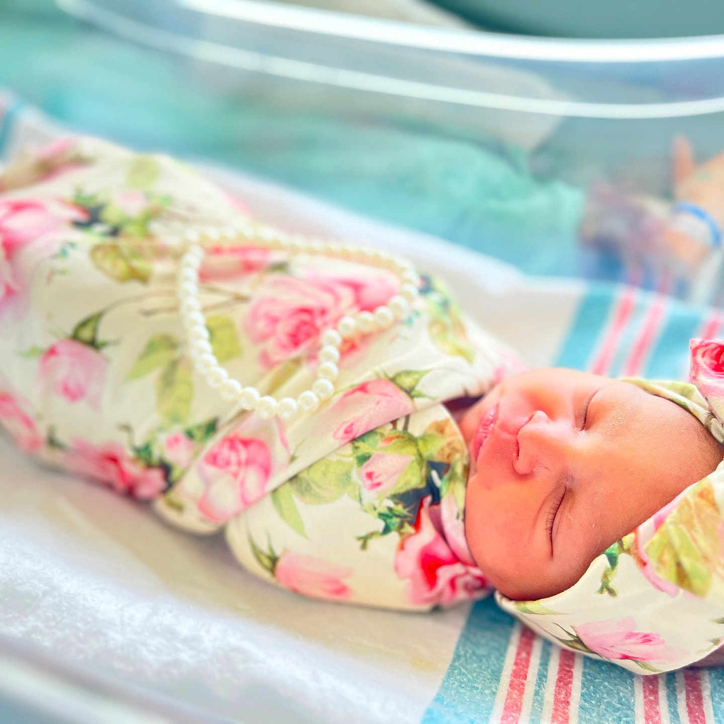 Genesis is registered to the contest to win money with this photo: newborn, baby, infant, sleeping, floral_blanket, headband, pearl_necklace, hospital_bassinet, soft_lighting, closeup, portrait, peaceful, cute, wrapped, child, human, resting, indoors, pink, white
